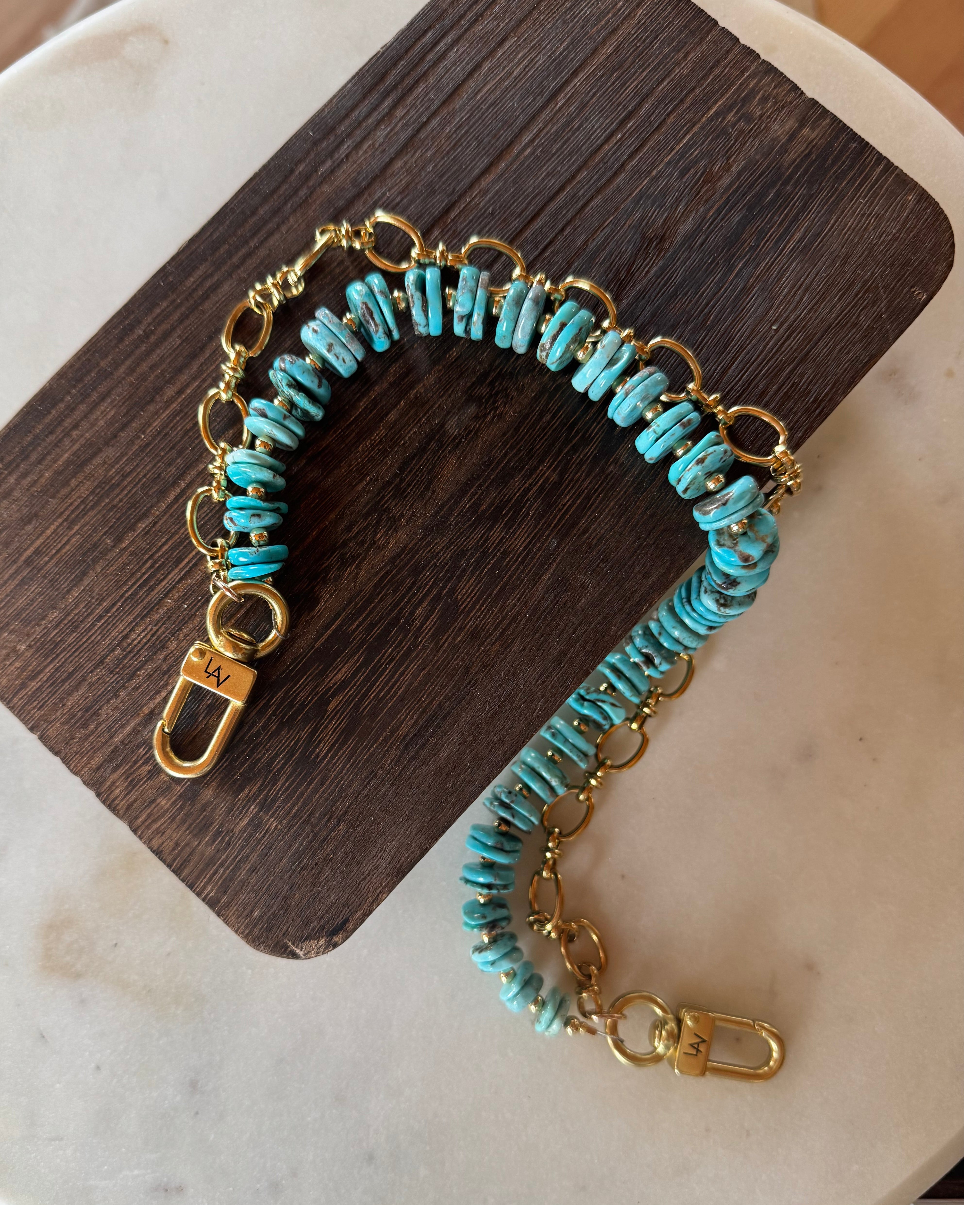 Turquoise beaded bag charm with gold chain on a wooden block, J Forks & Leather and Vodka