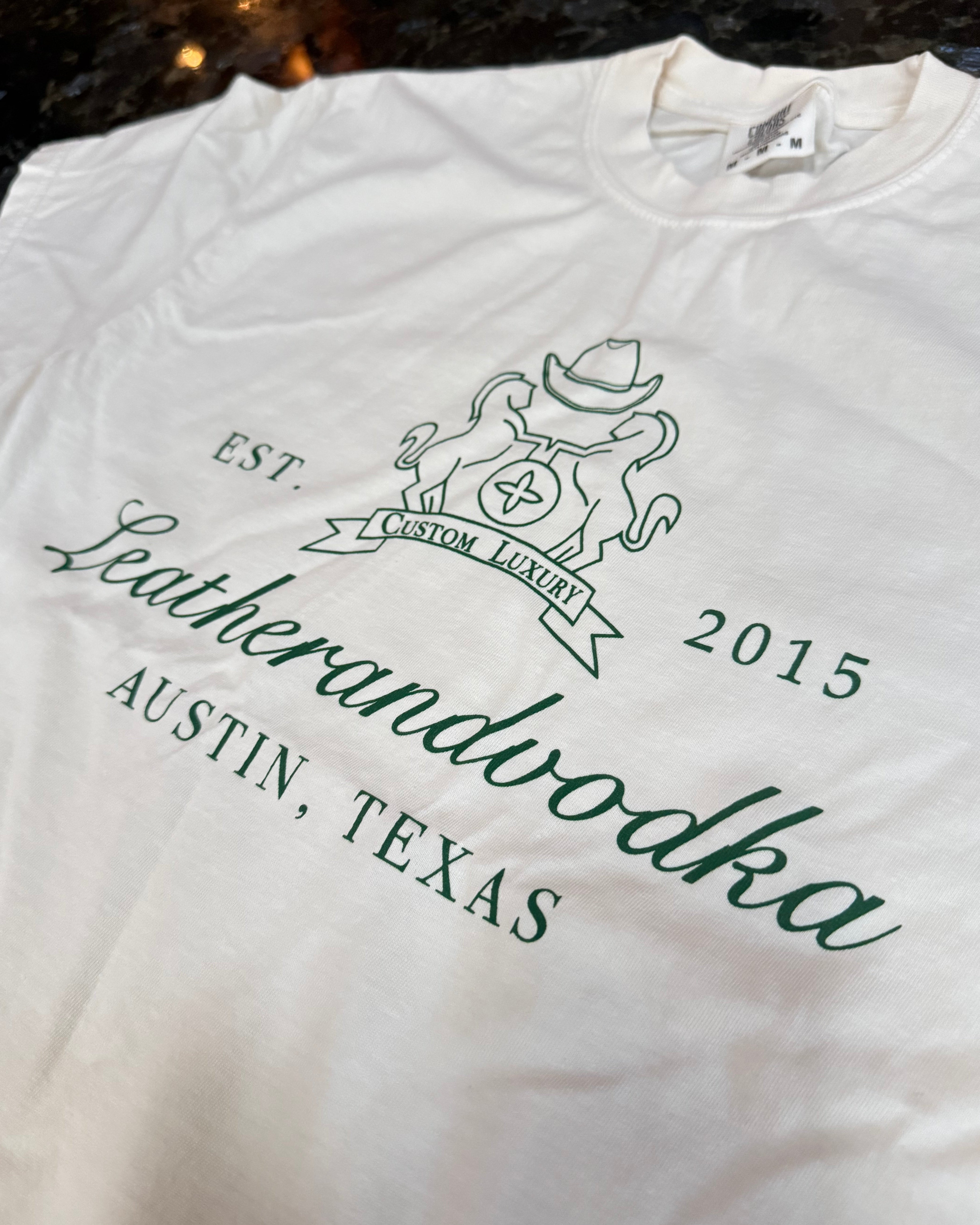 White shirt with 'Leatherandvodka' branding and text on a blurred background