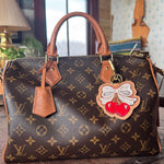 Designer handbag with a decorative charm on a wooden surface
