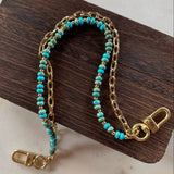Gold handbag chain with turquoise beads on a wooden block