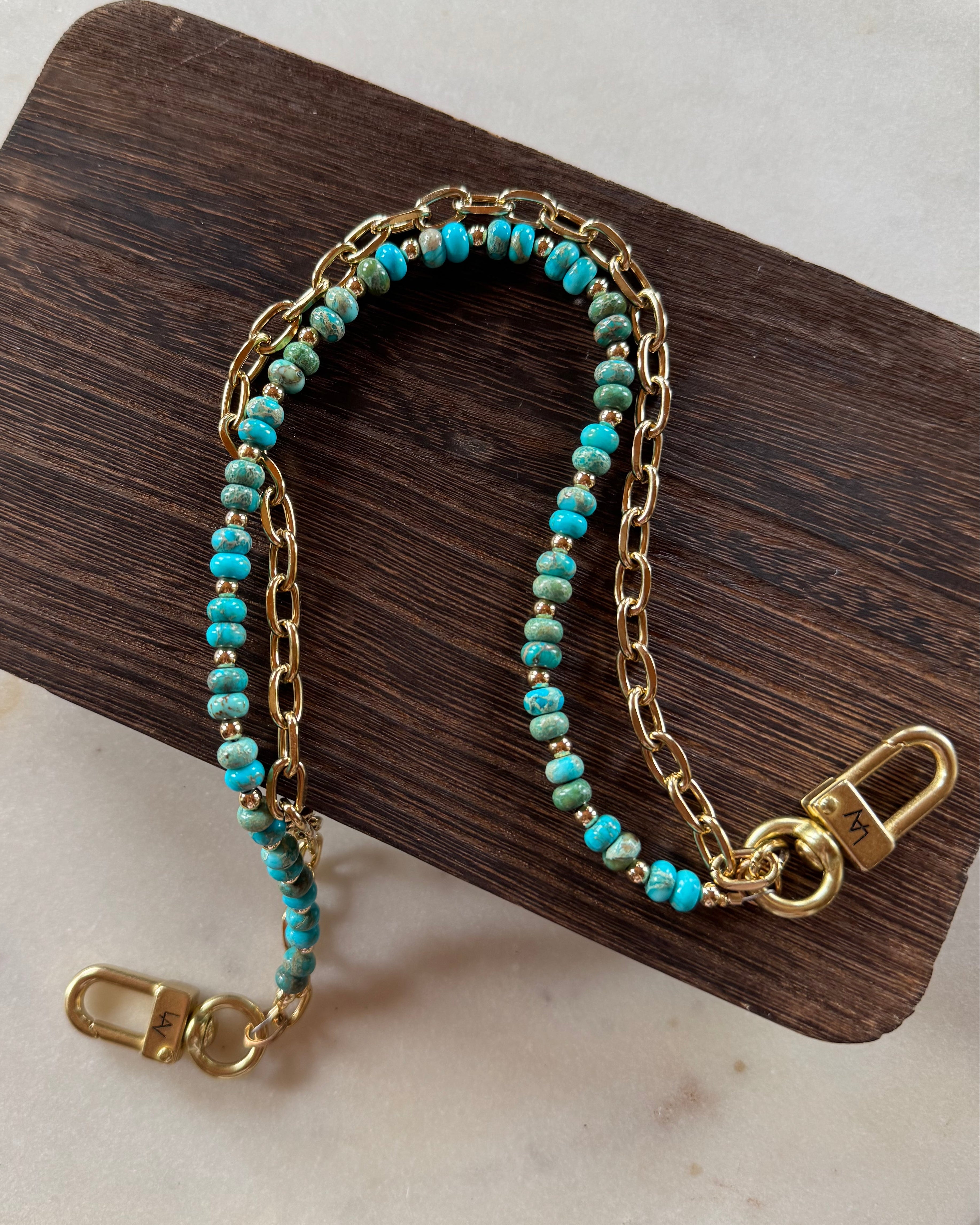 Gold handbag chain with turquoise beads on a wooden block