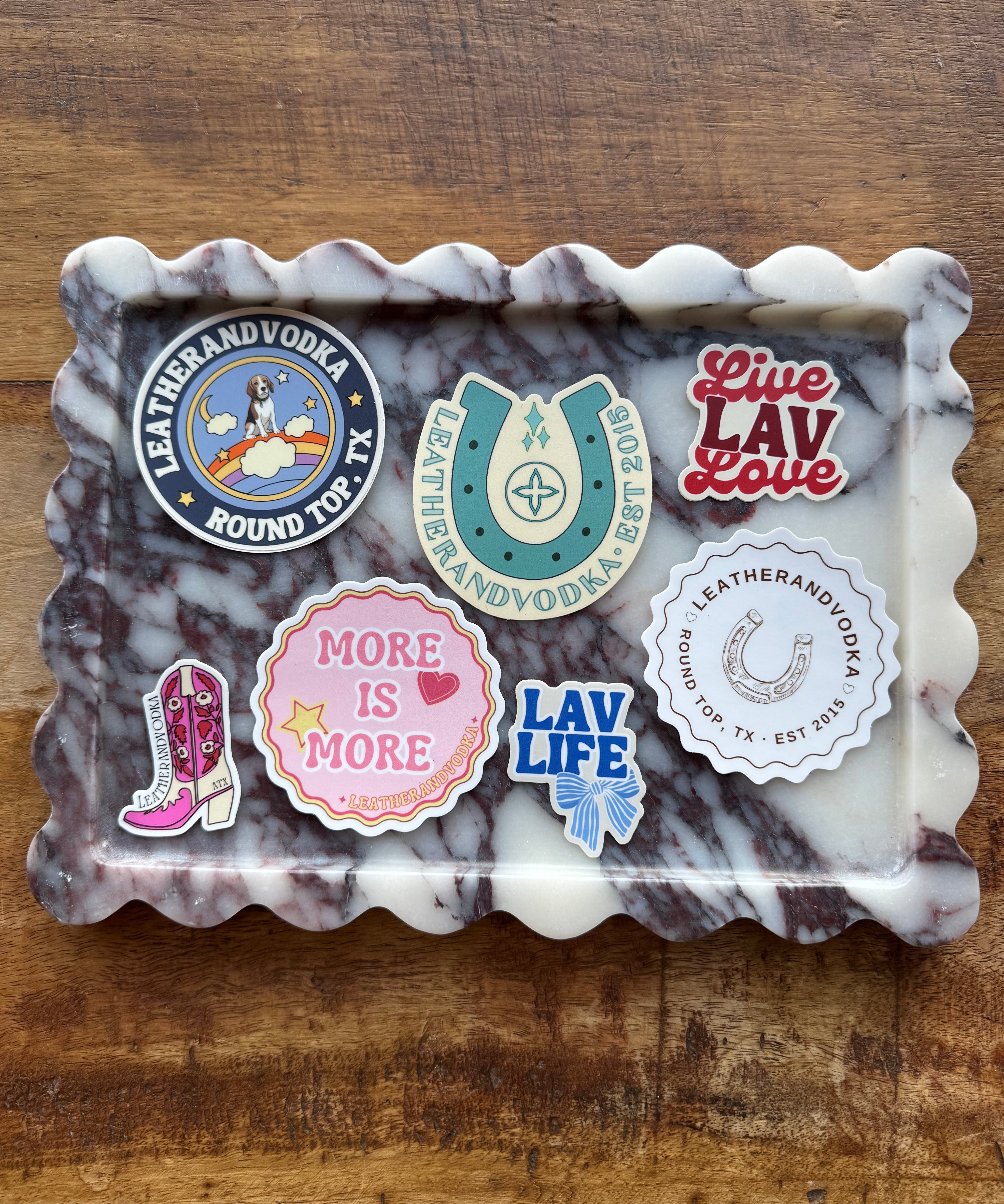 Marble-patterned tray with various stickers on a wooden surface