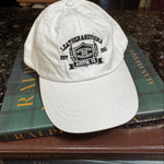 Whitebaseball cap with leatherandvodka embroidery sitting on books on marble counter top