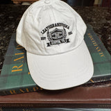 Whitebaseball cap with leatherandvodka embroidery sitting on books on marble counter top