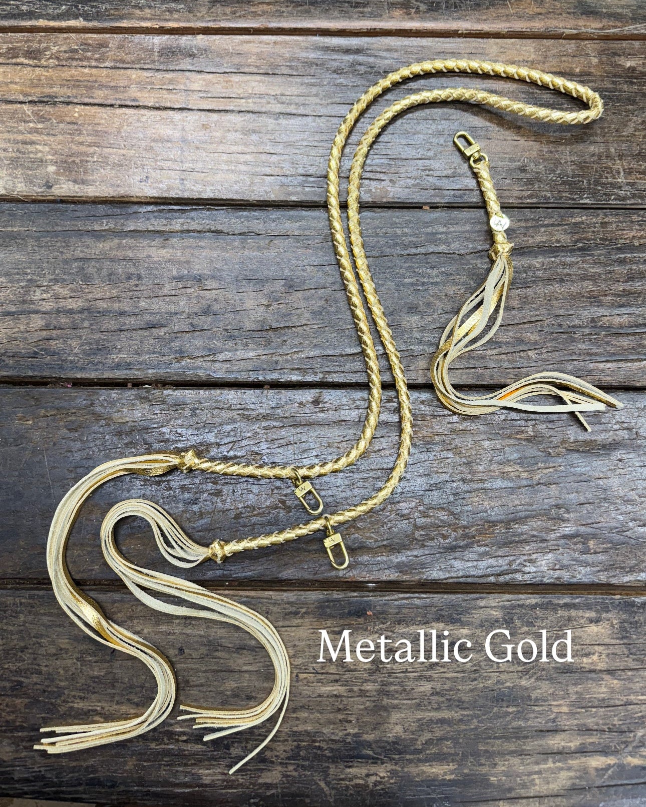 Metallic Gold Bag Strap, made with braided leather with matching snap on key chain, laying on wooden table. 