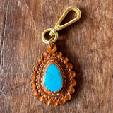 Leather keychain with blue stone and gold clasp on wooden surface