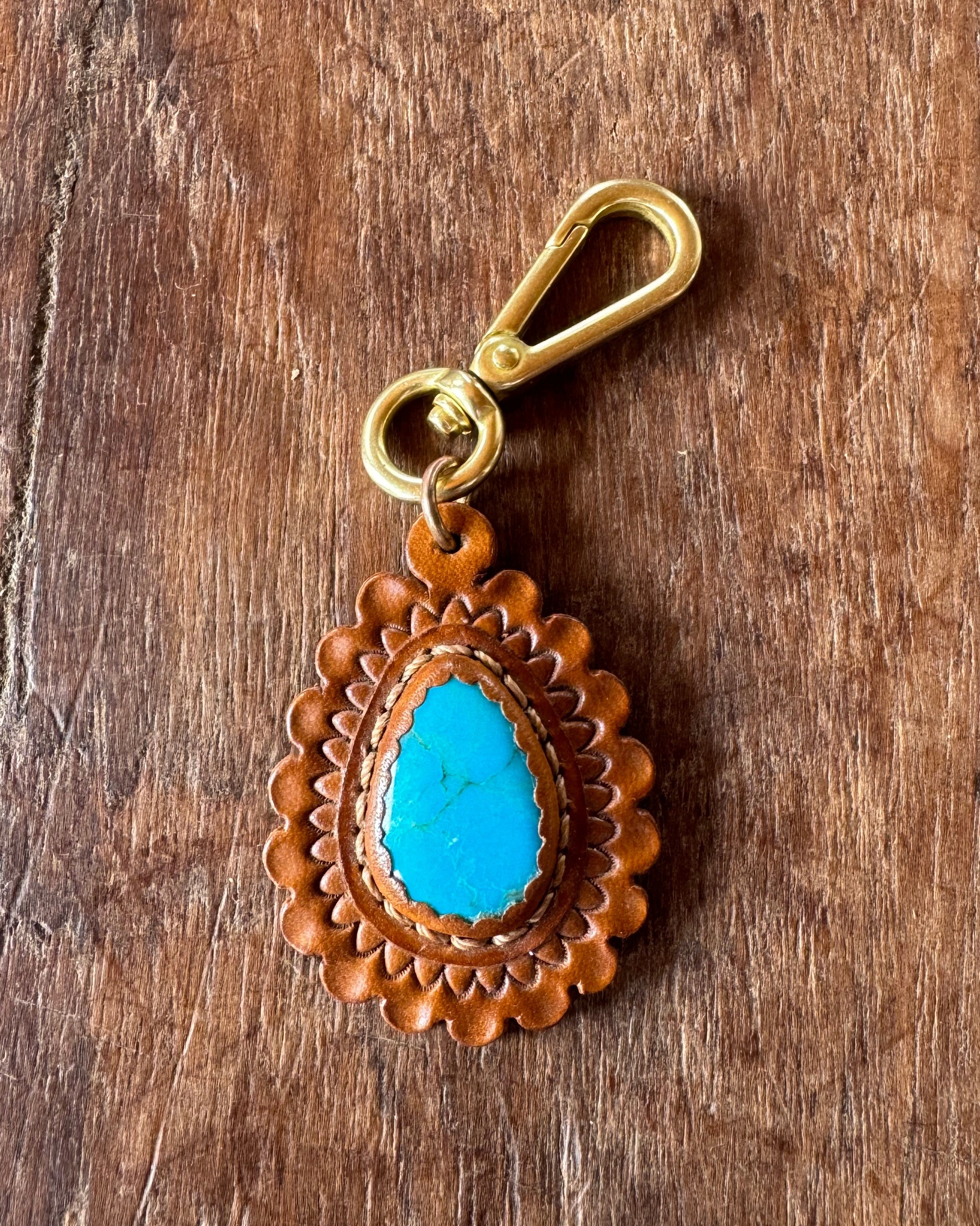 Leather keychain with blue stone and gold clasp on wooden surface