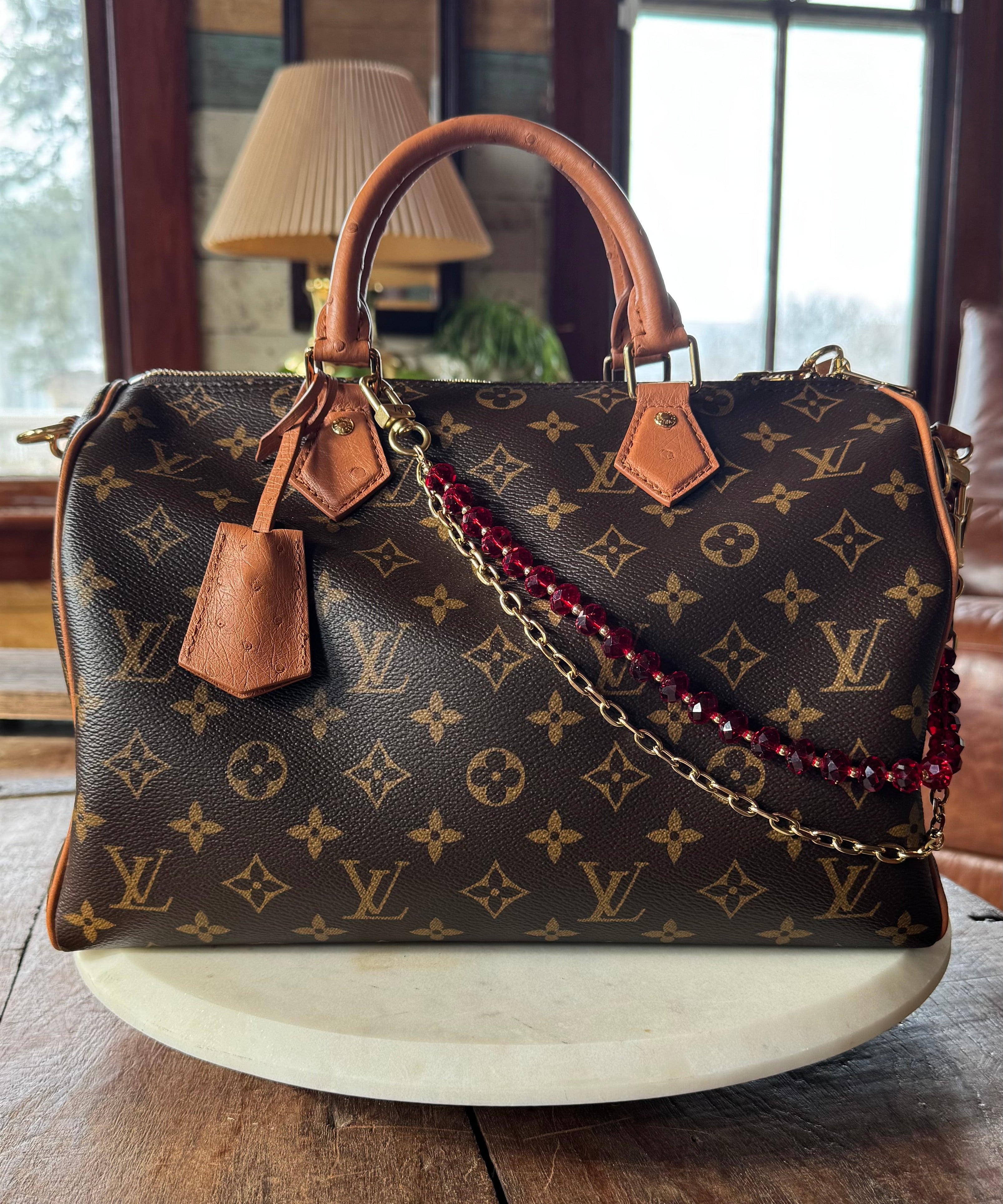 Designer handbag with monogram pattern on a wooden surface. LAV x JForks Red Crystal Chain