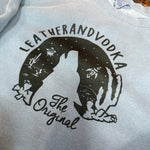 Gray sweatshirt with black graphic design and text on a textured surface