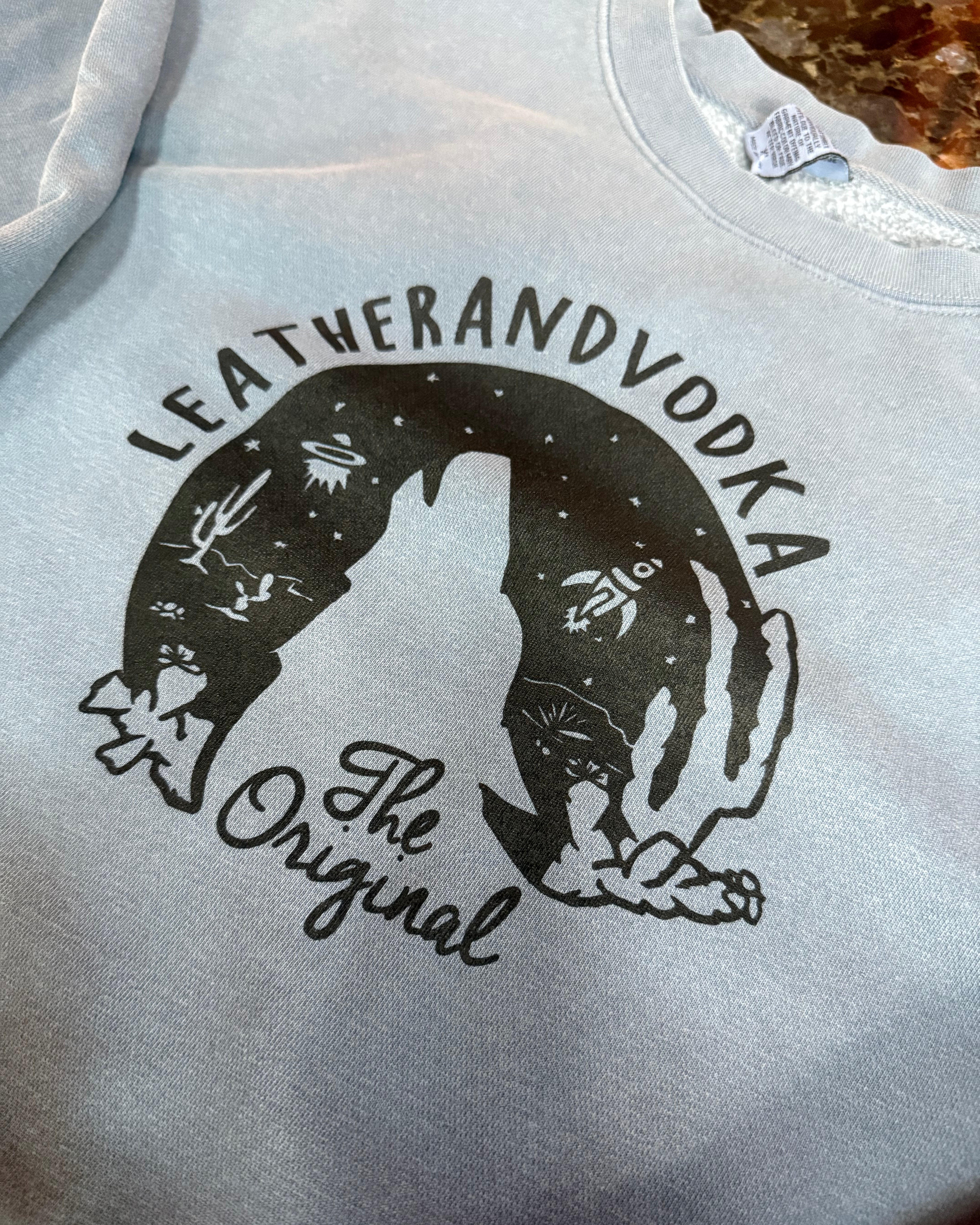 Gray sweatshirt with black graphic design and text on a textured surface