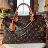 Designer handbag with monogram pattern on a wooden surface