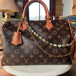 Designer handbag with monogram pattern on a wooden surface with bag charm, Leatherandvodka and JForks