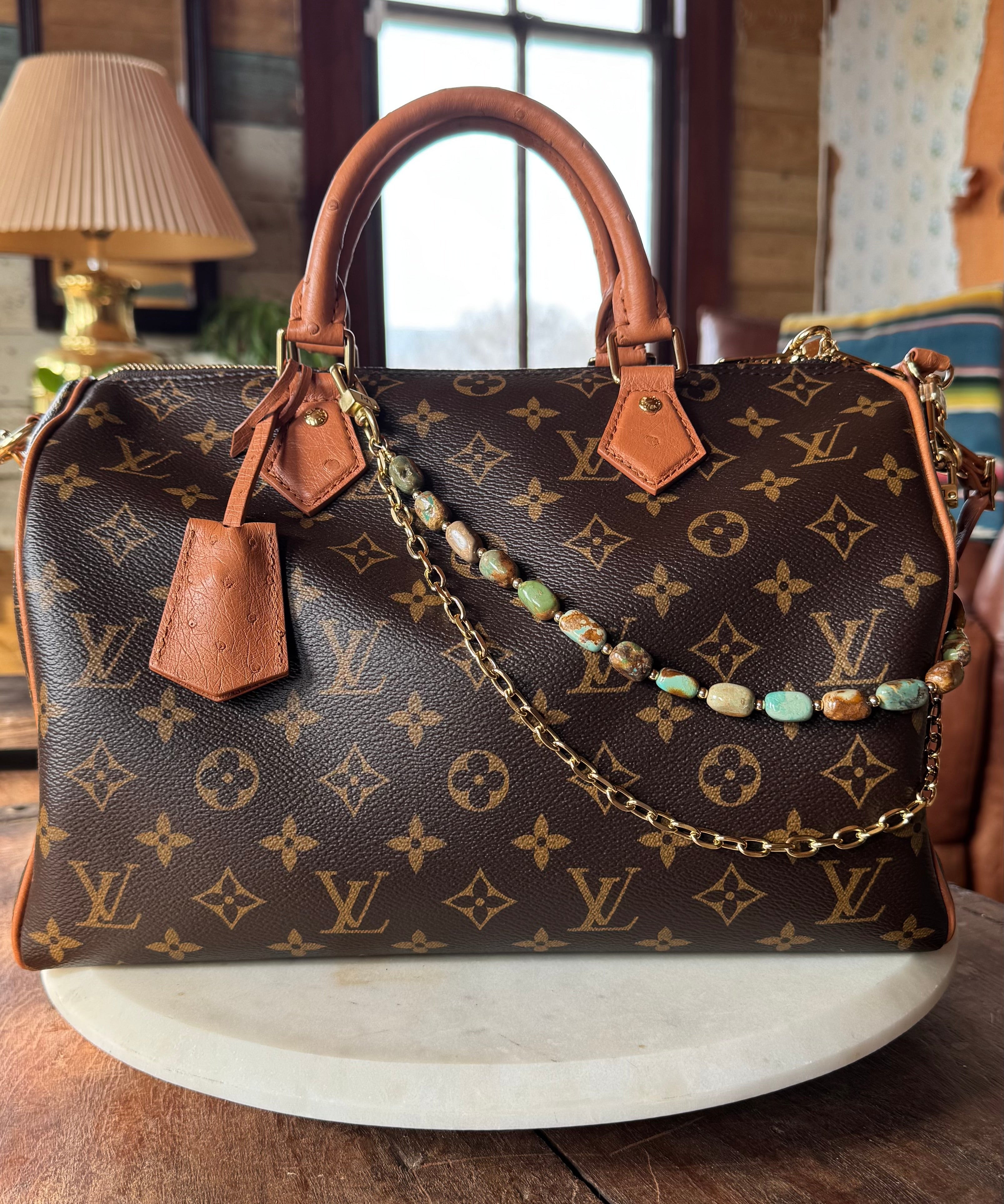 Designer handbag with monogram pattern on a wooden surface with bag charm, Leatherandvodka and JForks