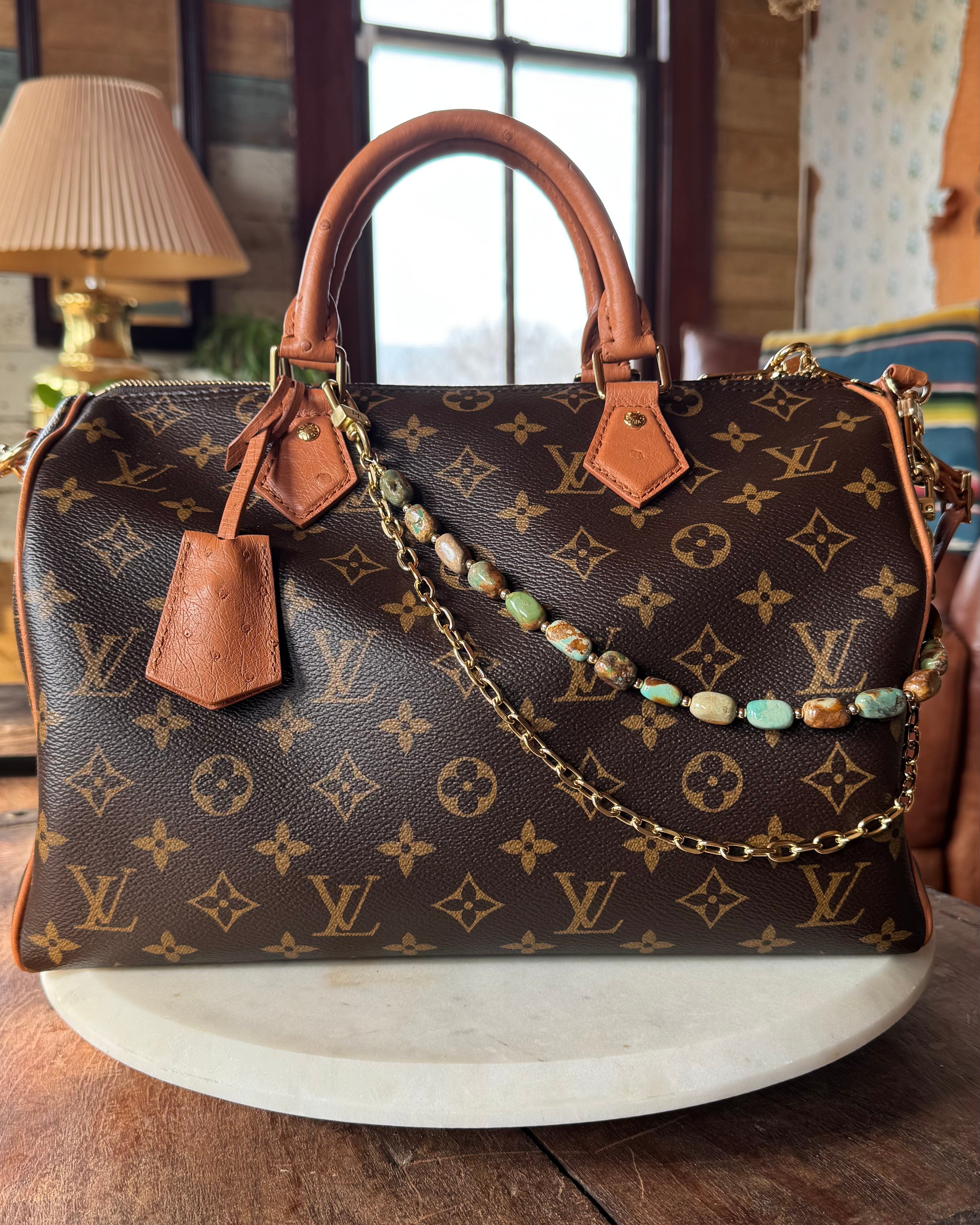 Designer handbag with monogram pattern on a wooden surface with bag charm, Leatherandvodka and JForks