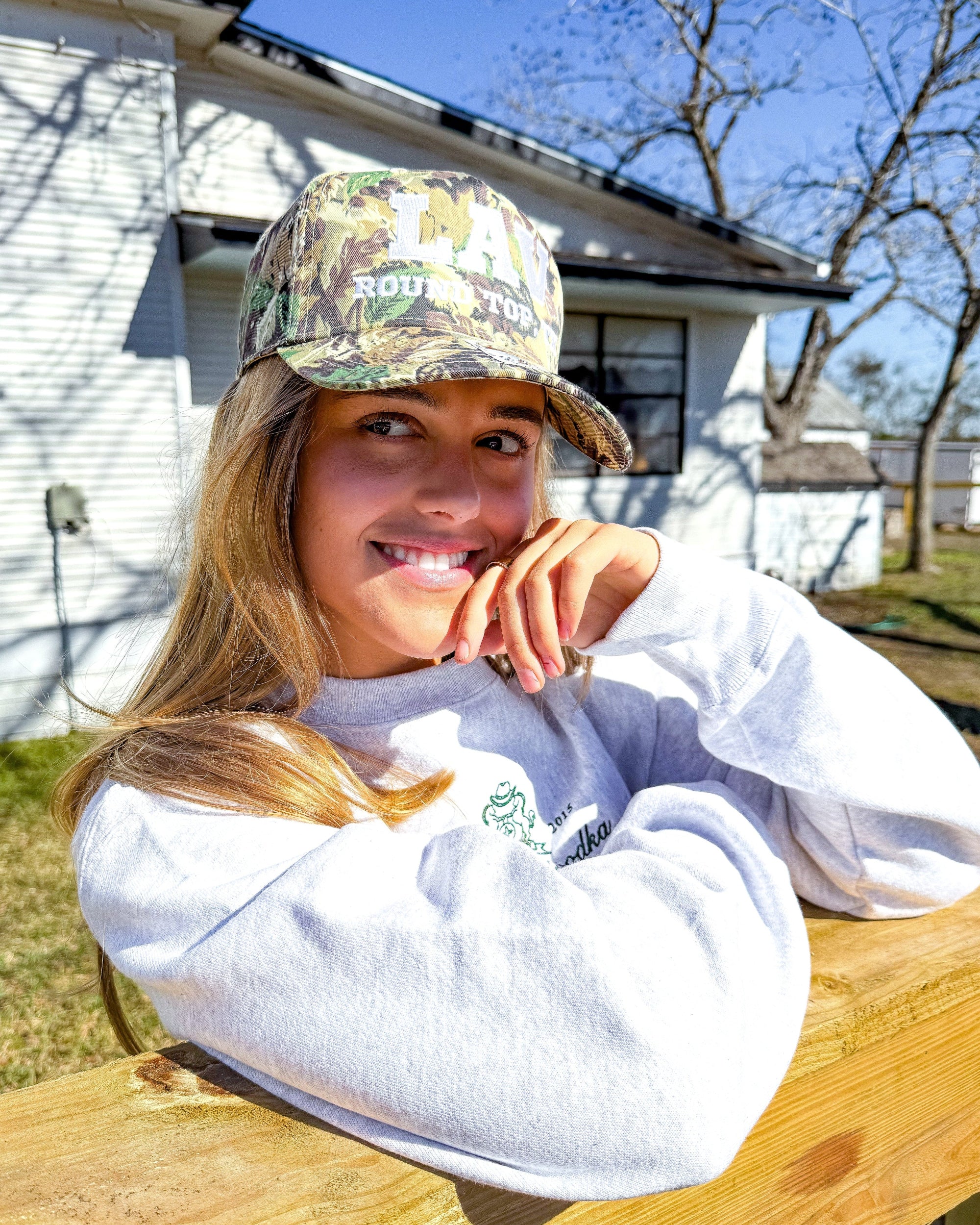 Person wearing a camouflage LAV cap and white sweatshirt at Zapp Hall, in Round Top Texas