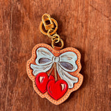 Decorative keychain with bow and heart design on a wooden surface
