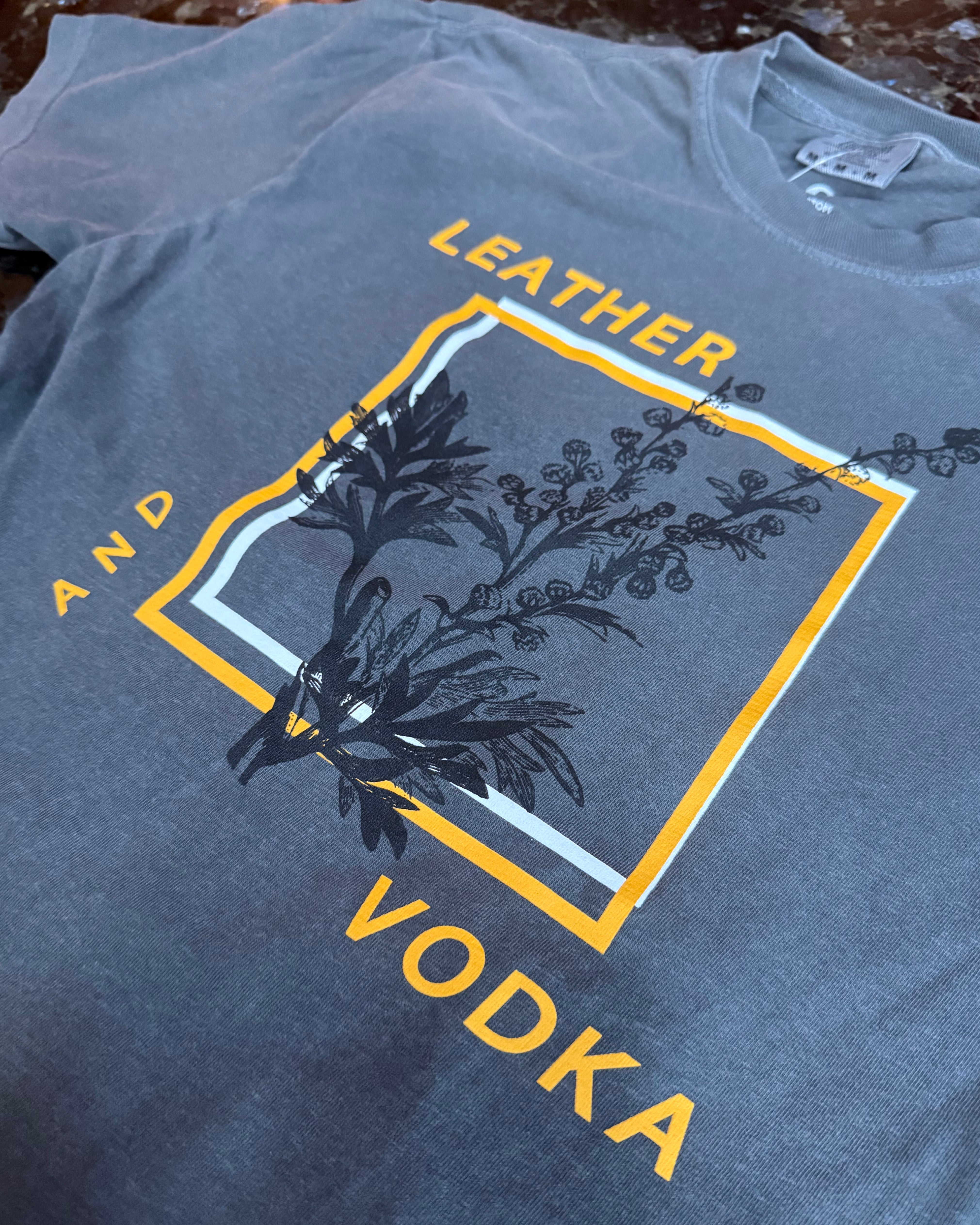 Gray tank top with 'Leather and Vodka' graphic design on a textured surface