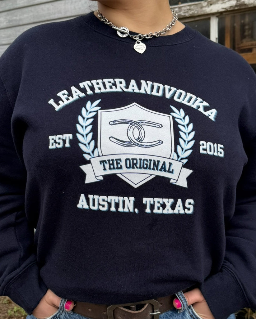 A person wearing a navy sweatshirt with 'LEATHERANDVOODKA' and 'THE ORIGINAL AUSTIN, TEXAS' printed on the front.