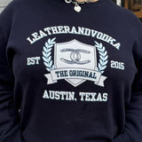 A person wearing a navy sweatshirt with 'LEATHERANDVOODKA' and 'THE ORIGINAL AUSTIN, TEXAS' printed on the front.