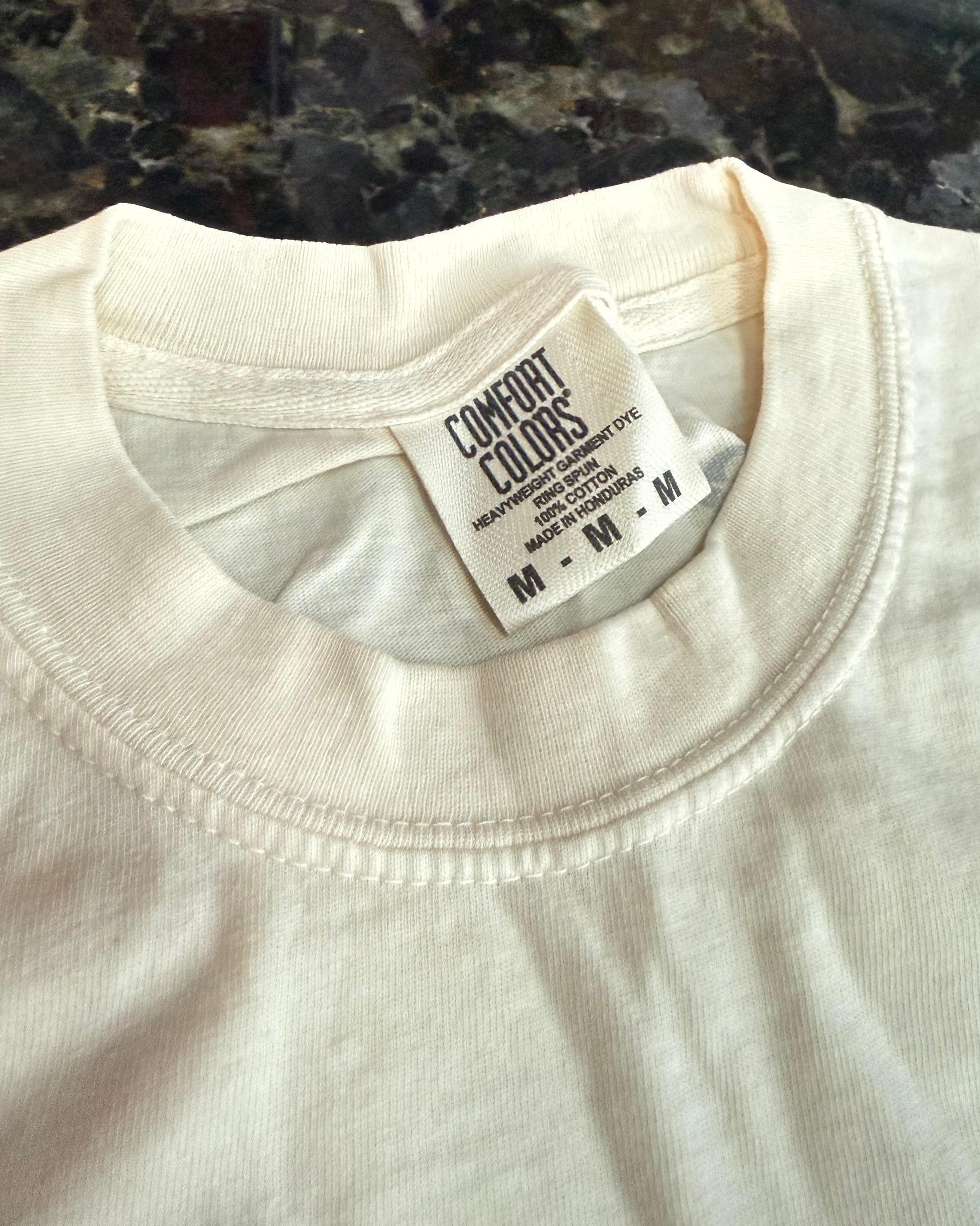 Close-up of a white shirt with a tag on a dark surface