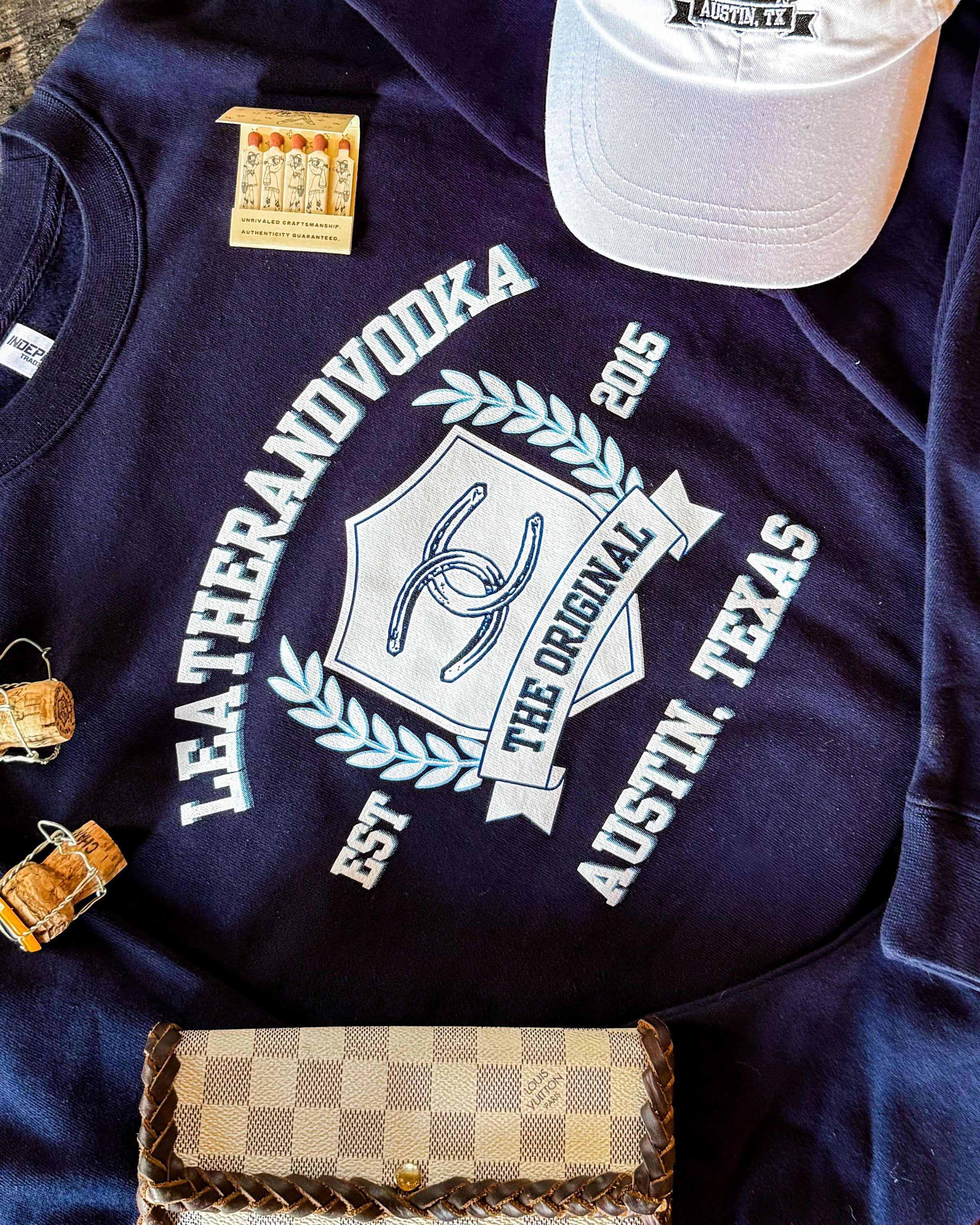 Blue crewneck with words Leatherandvodka laying on marble countertop