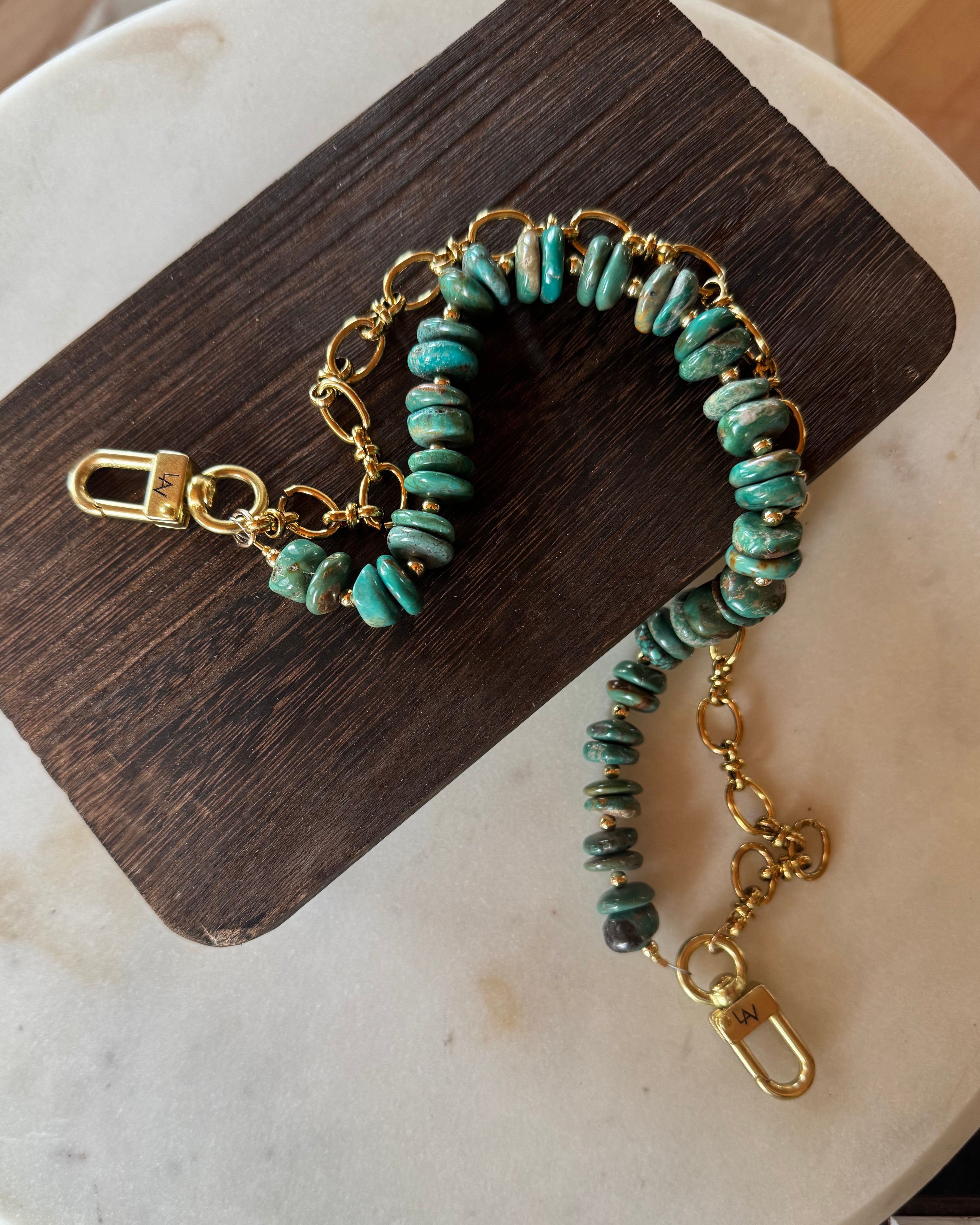 Turquoise beaded bag chain with gold chain on a wooden block, J Forks & Leather and Vodka