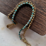 Gold handbag chain with turquoise beads on a wooden block