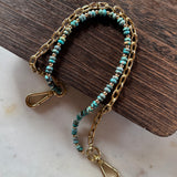 Gold handbag chain with turquoise beads on a wooden block