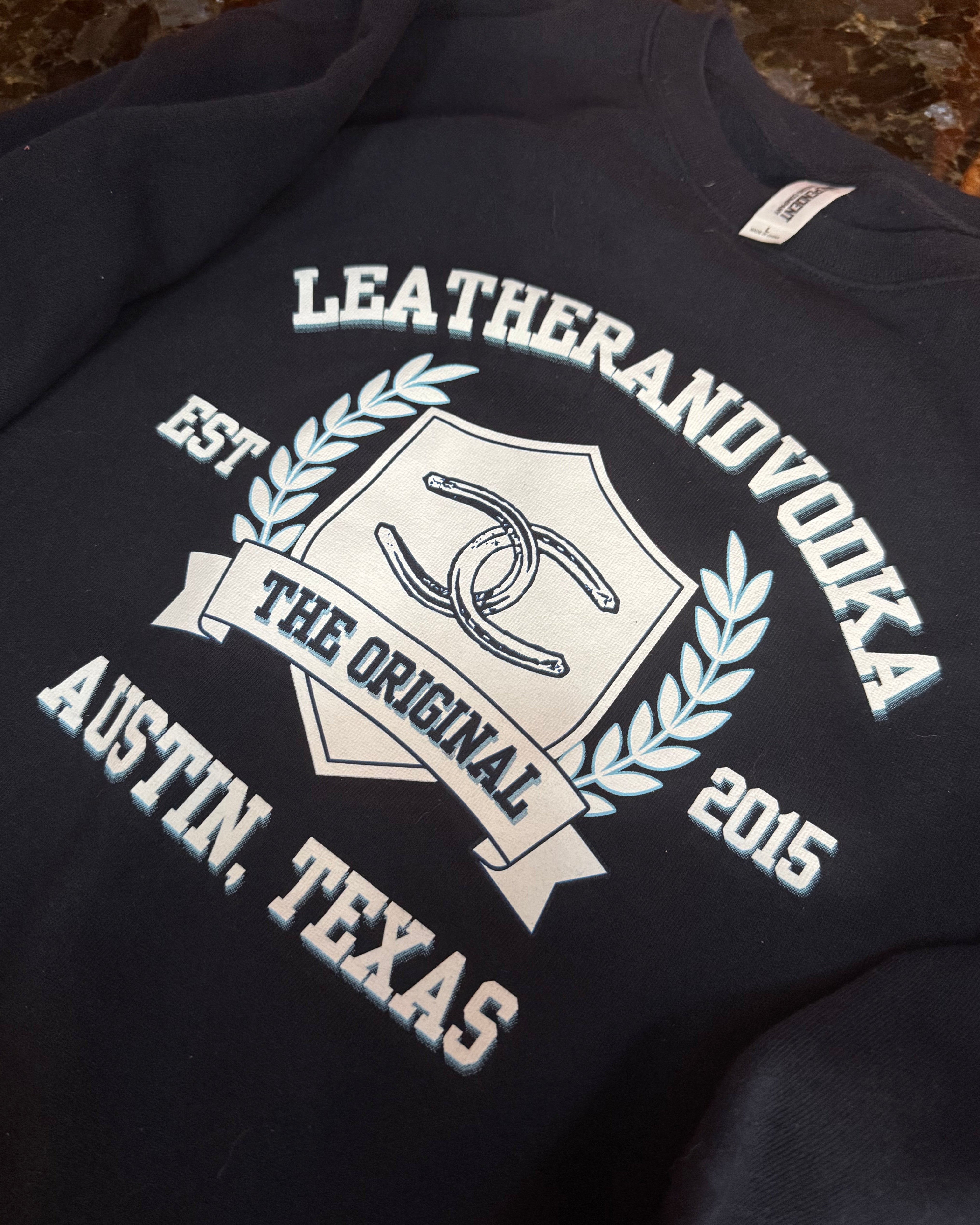 Black sweatshirt with white text and logo on a textured surface