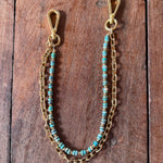 Gold chain with turquoise beads on a wooden surface