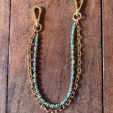 Gold chain with turquoise beads on a wooden surface