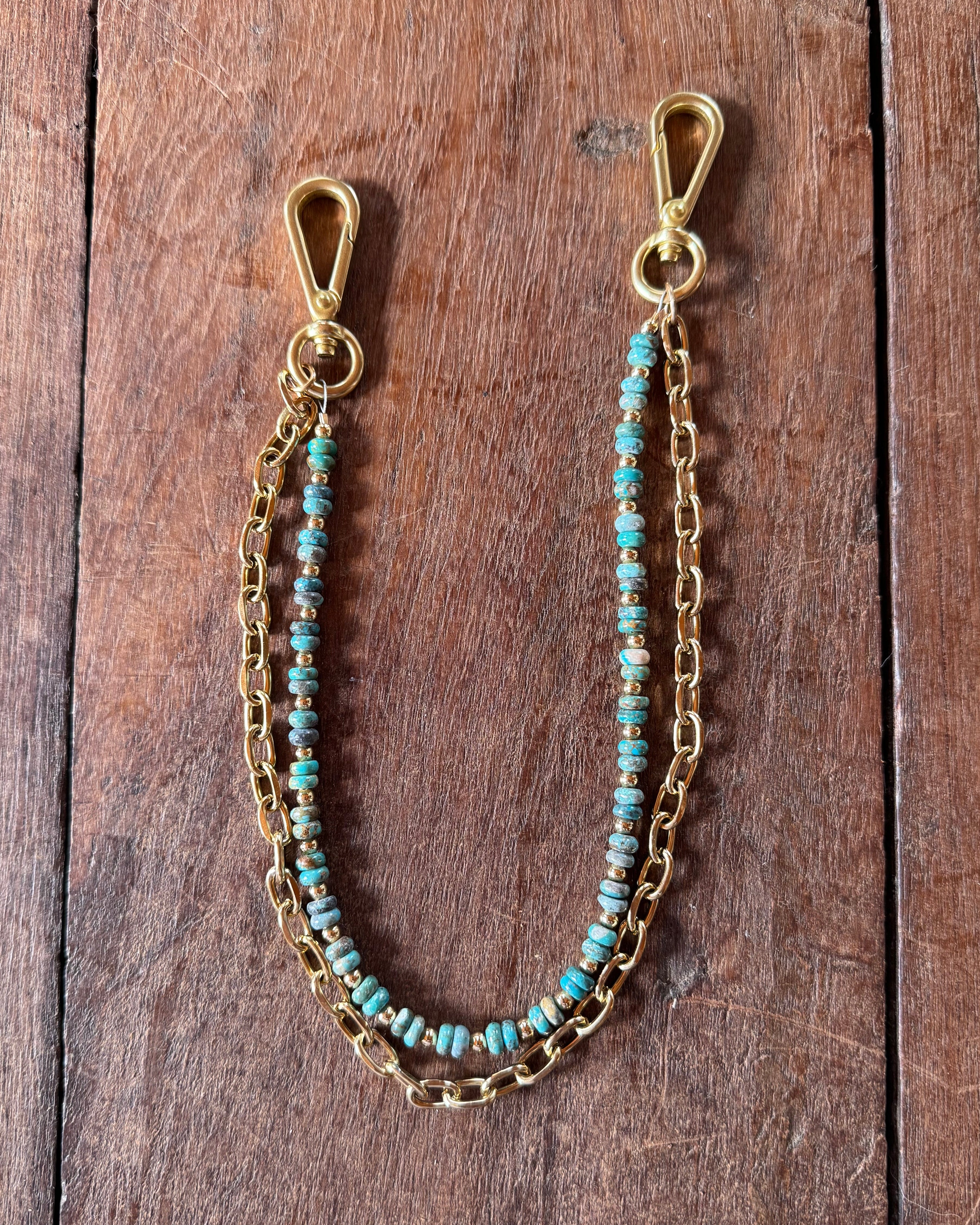 Gold chain with turquoise beads on a wooden surface