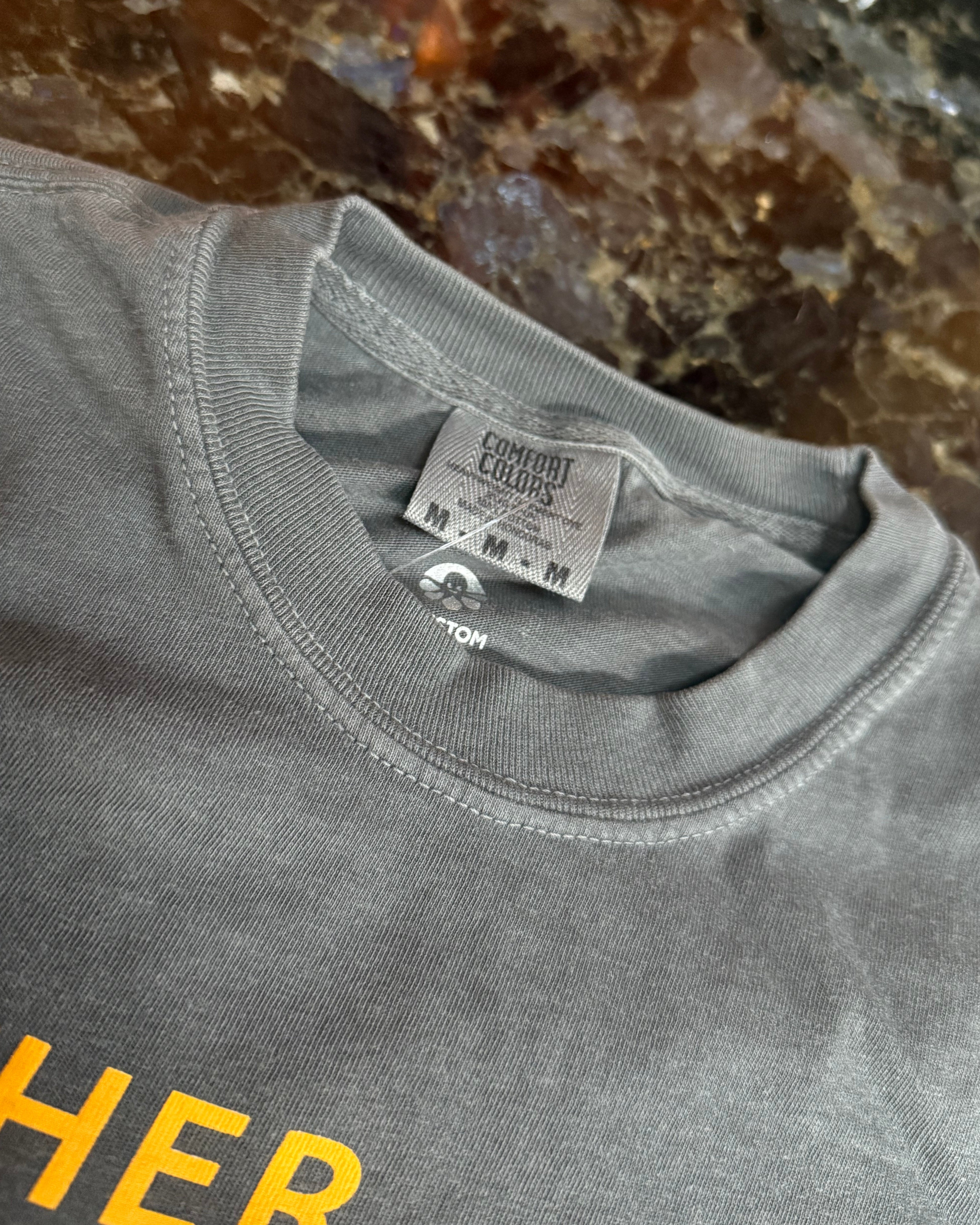 Gray t-shirt with a brand tag on a marble surface