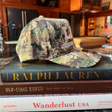 Camouflage-patterned LAV Hat on a stack of books 