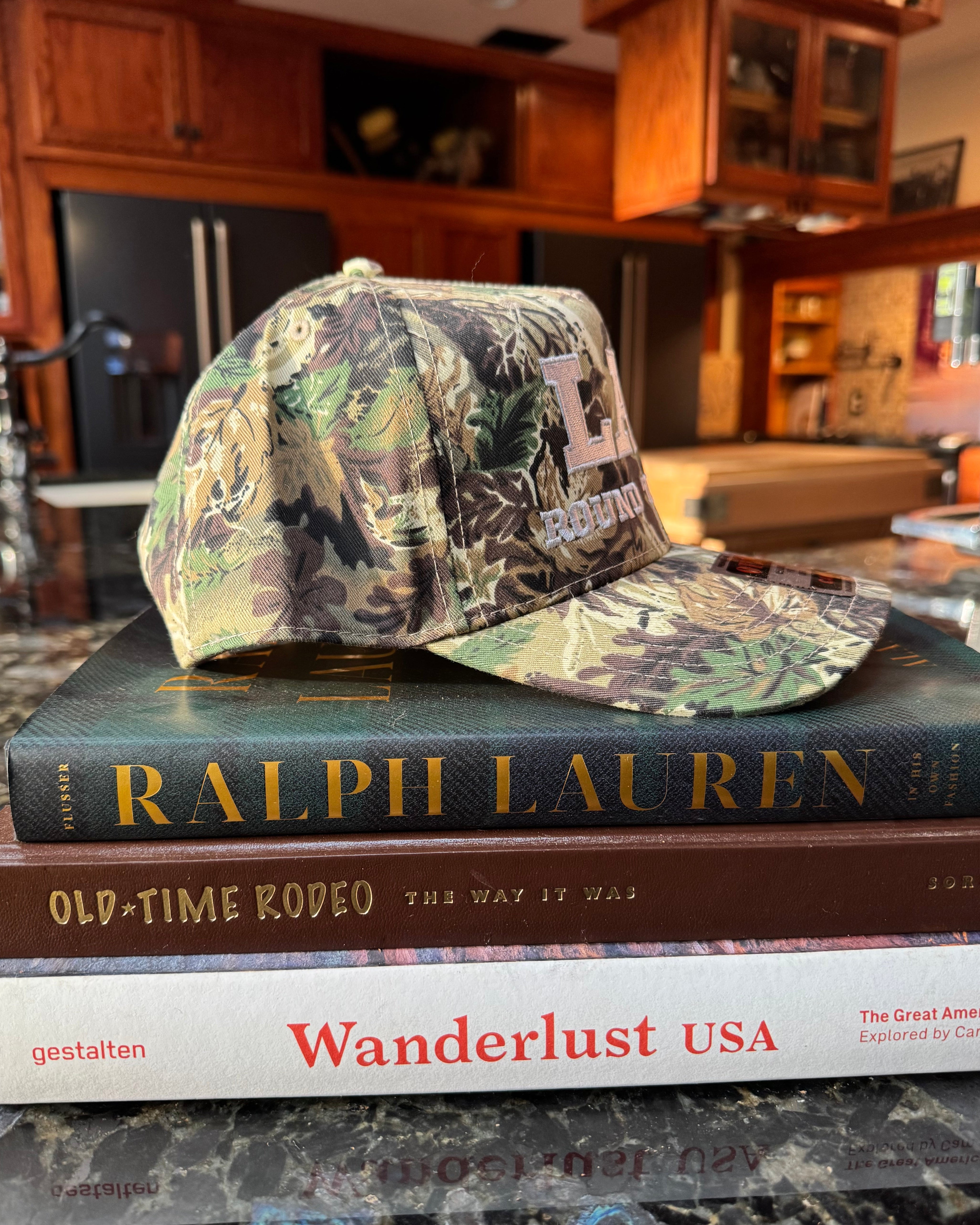 Camouflage-patterned LAV Hat on a stack of books 