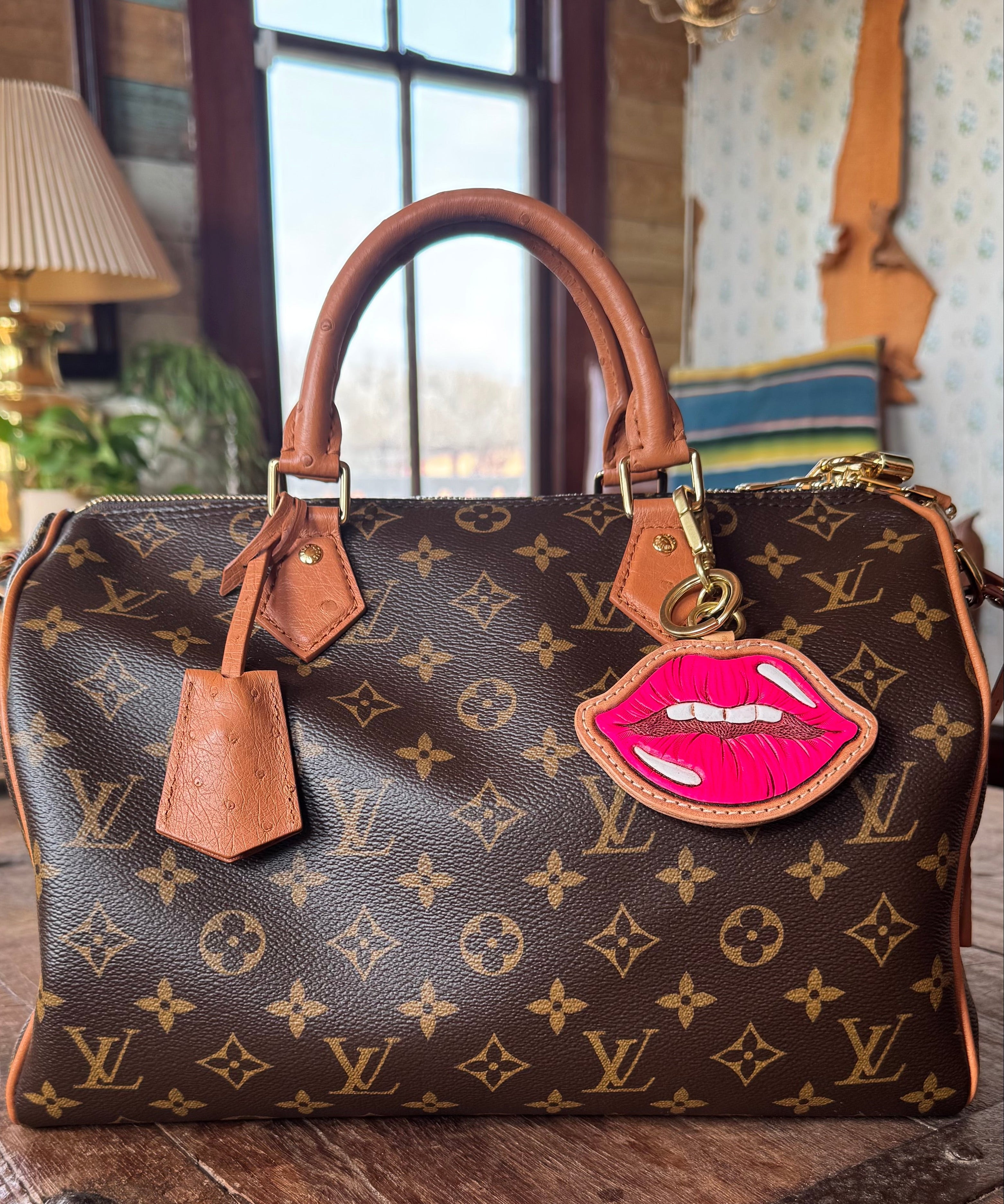 Designer handbag with a unique lip-shaped charm on a wooden surface