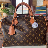 Designer handbag with monogram pattern on a marble surface