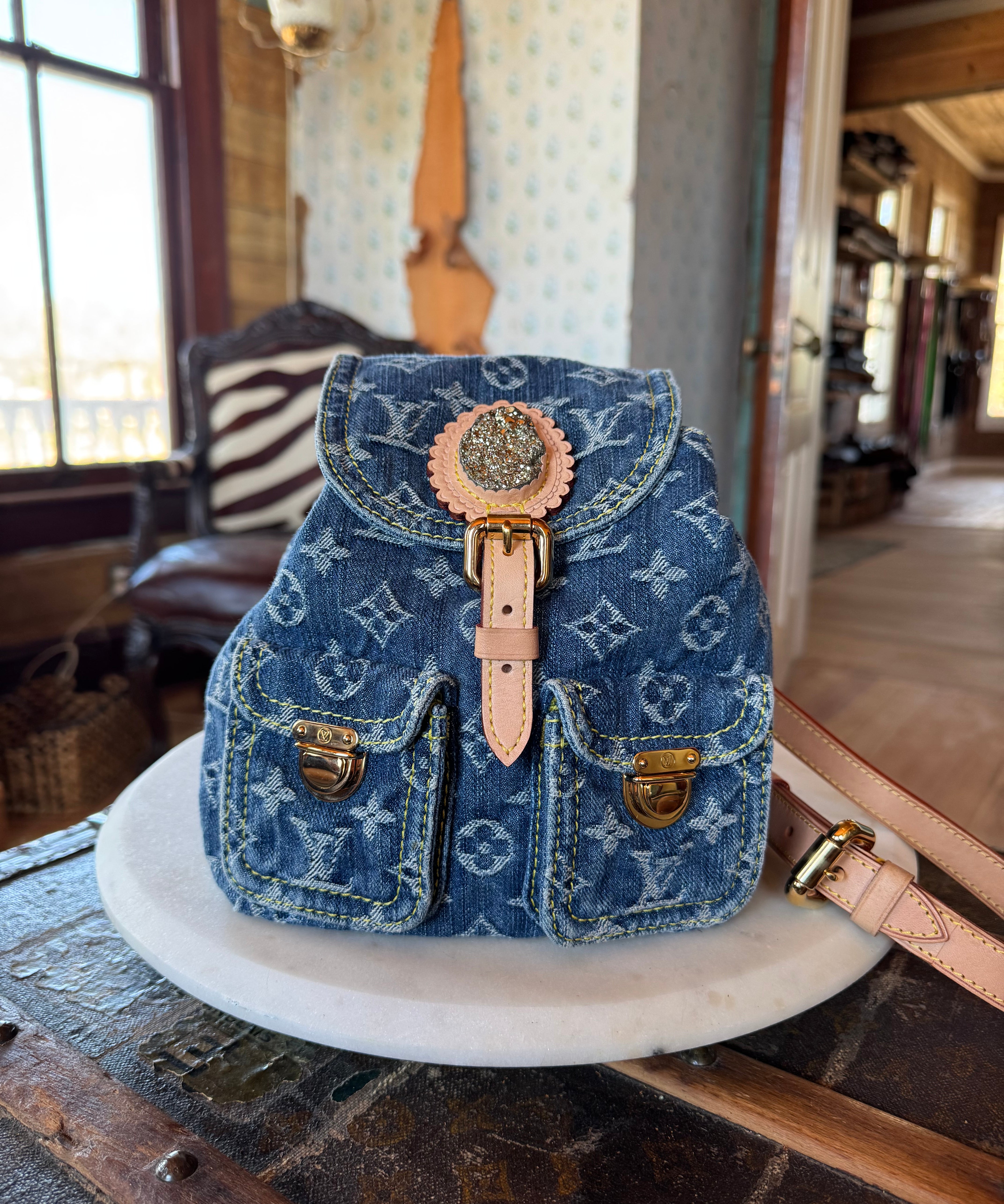 Custom luxury designer handbag with gemstone, denim pattern and gold hardware on a white surface.