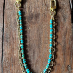 Turquoise beaded chain with gold clasp on a wooden surface