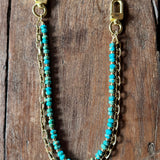 Turquoise beaded chain with gold clasp on a wooden surface