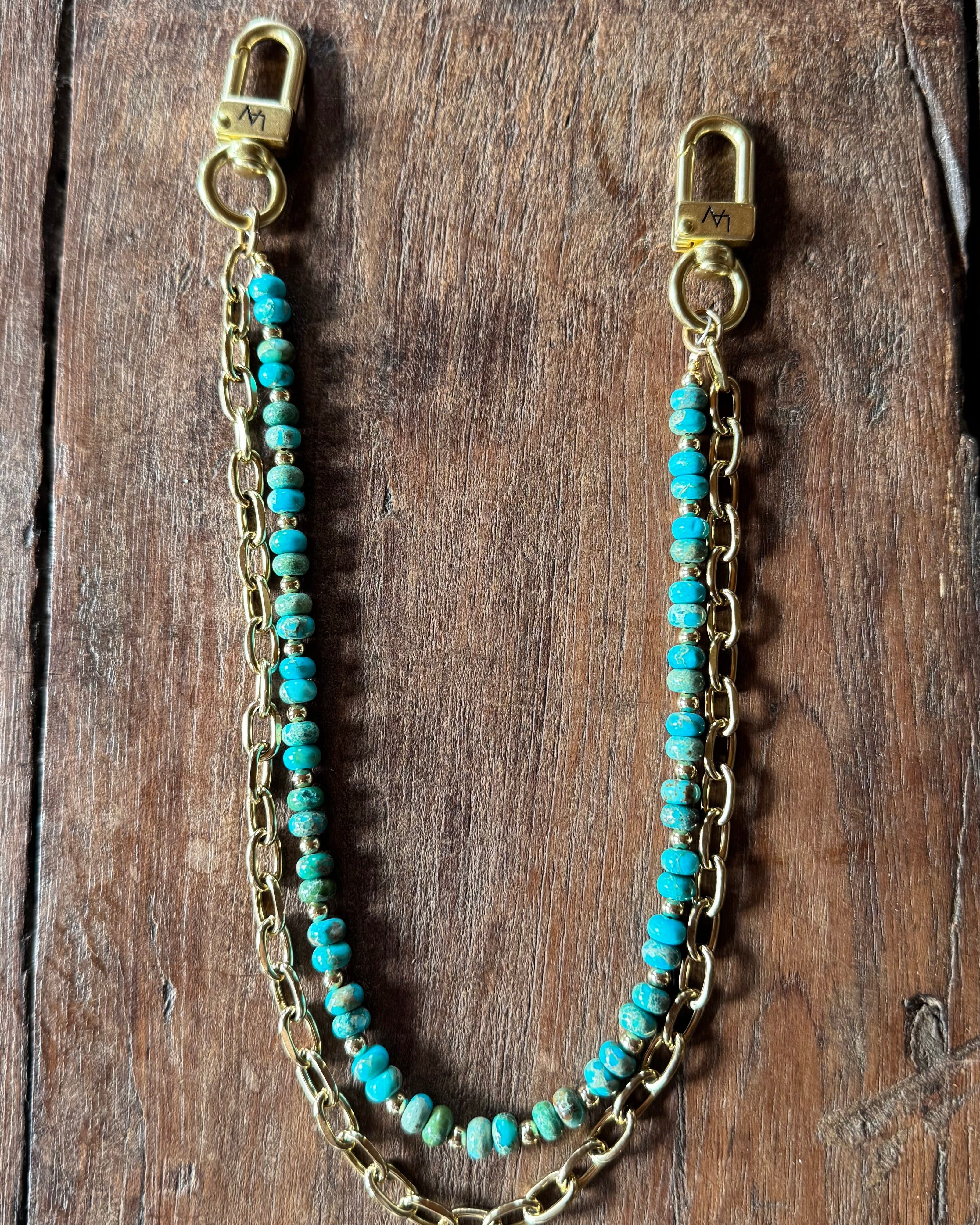 Turquoise beaded chain with gold clasp on a wooden surface