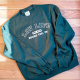 Green sweatshirt with LAV Life, Round Top, Texas text on a wooden surface