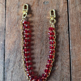 LAV x JForks Red Crystal Chain with clips to attach to handbag, sitting on wood and marble surface. 