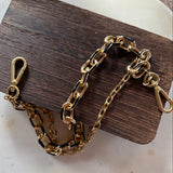 Gold chain bracelet on a wooden block with a white background