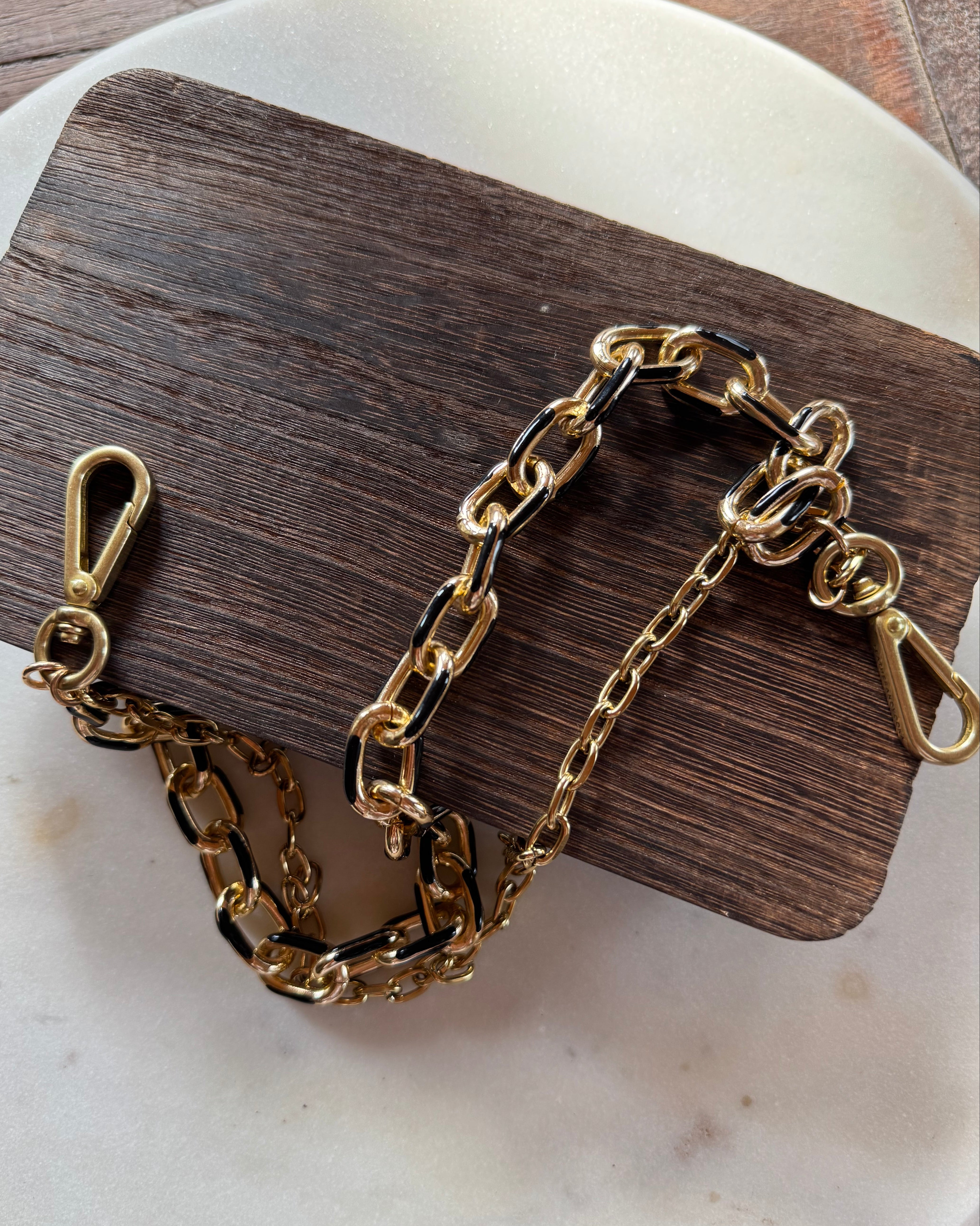 Gold chain bracelet on a wooden block with a white background