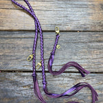 Metallic Purple Bag Strap, made with braided leather with matching snap on key chain, laying on wooden table. 