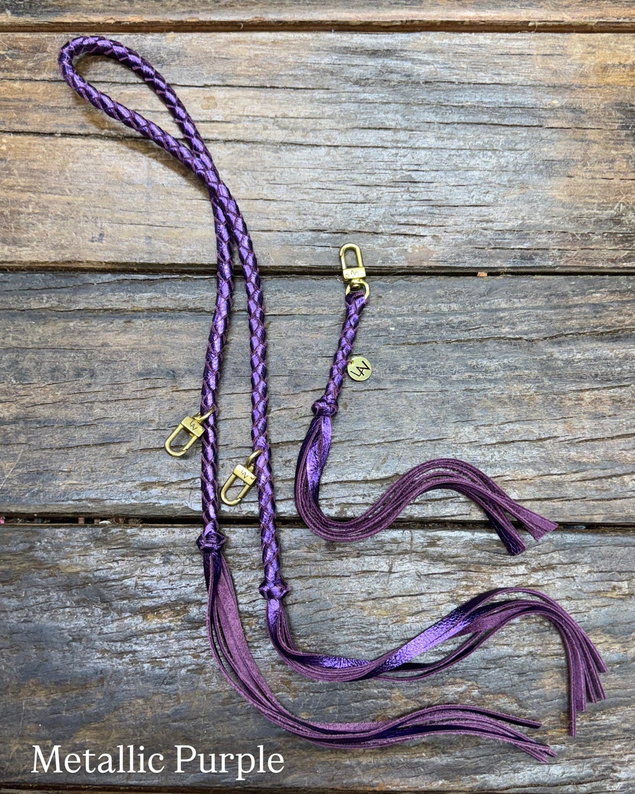 Metallic Purple Bag Strap, made with braided leather with matching snap on key chain, laying on wooden table. 