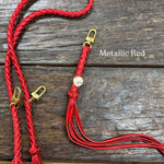 Metallic Red Bag Strap, made with braided leather with matching snap on key chain, laying on wooden table. 