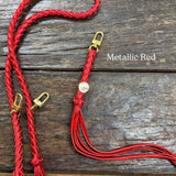 Metallic Red Bag Strap, made with braided leather with matching snap on key chain, laying on wooden table. 