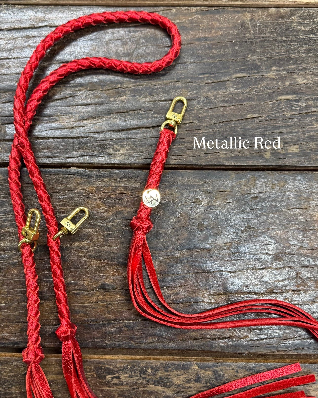 Metallic Red Bag Strap, made with braided leather with matching snap on key chain, laying on wooden table. 